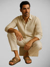 Modelo masculino vestindo sandália Birken bege com duas tiras e fivelas metálicas, em estilo clássico e casual sofisticado
