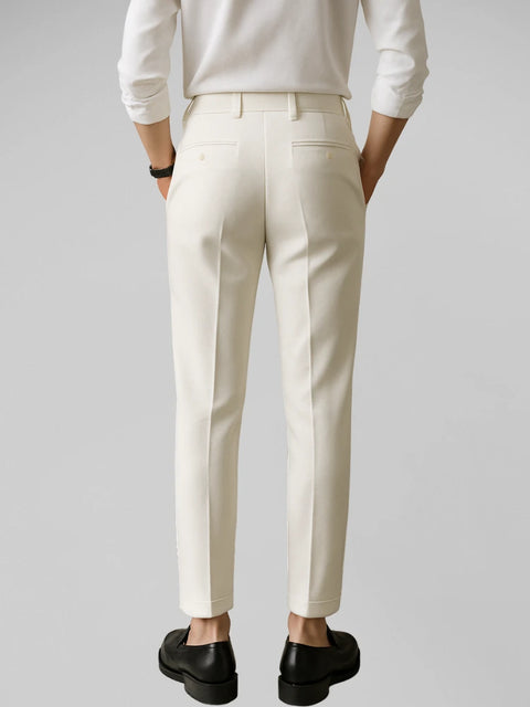 Close do corpo de homem vestindo calça de alfaiataria ivory com camisa branca, fundo branco e visual refinado.